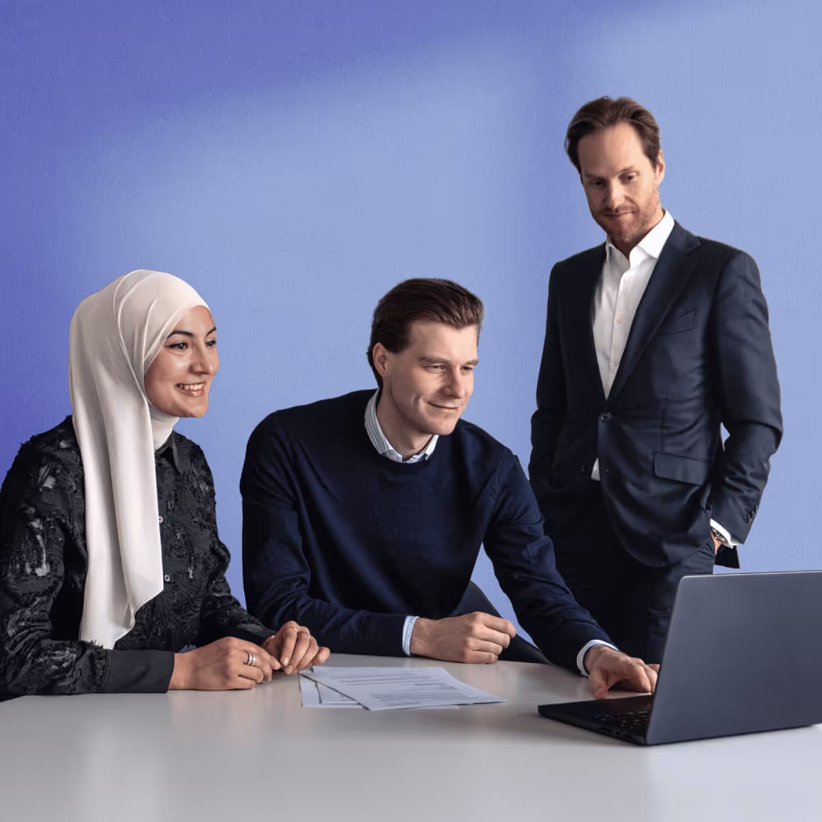 Drei Geschäftsleute arbeiten zusammen an einem Laptop im Büro