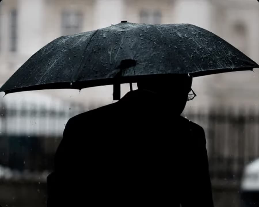 Schwarze Silhouette mit Regenschirm an einem regnerischen, trüben Tag