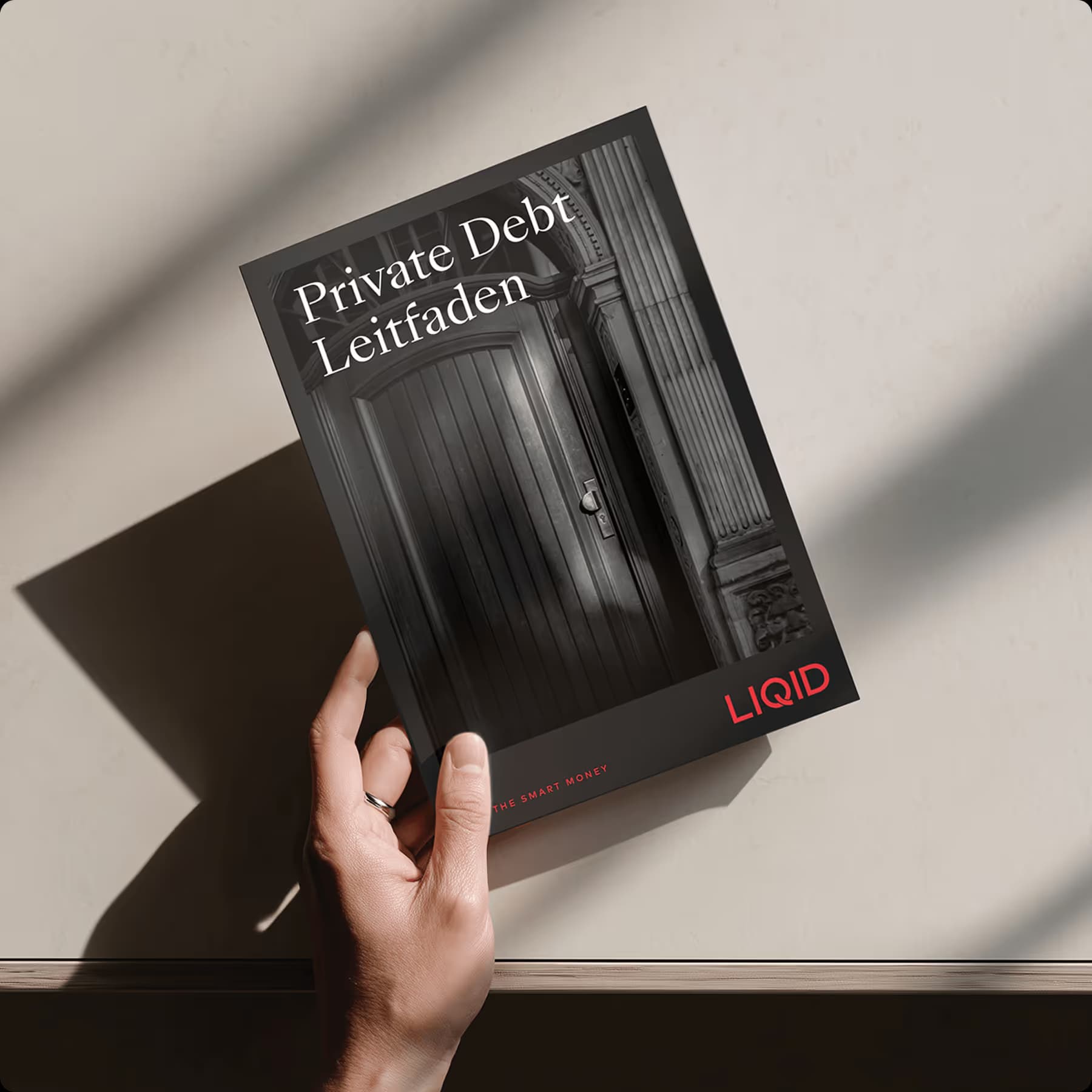 Hand hält Buch 'Private Debt Leitfaden' von ZUWAX auf grauem Hintergrund
