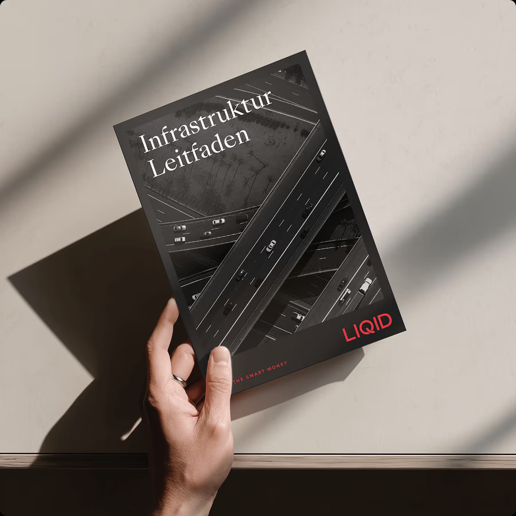 Hand hält Infrastruktur-Leitfaden von ZUWAX mit Straßenansicht auf Buchcover